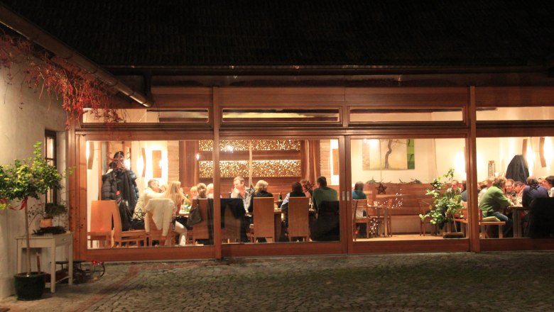 A cozy wine tavern with guests sitting at tables, visible through large windows.