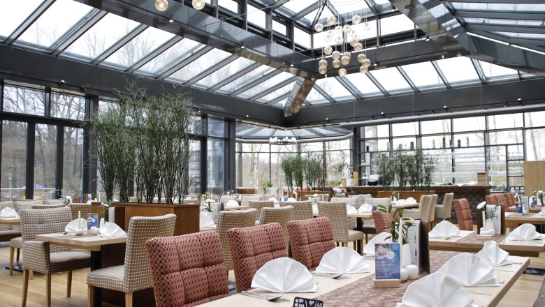 Interior view of a modern restaurant with glass roof and covered tables.
