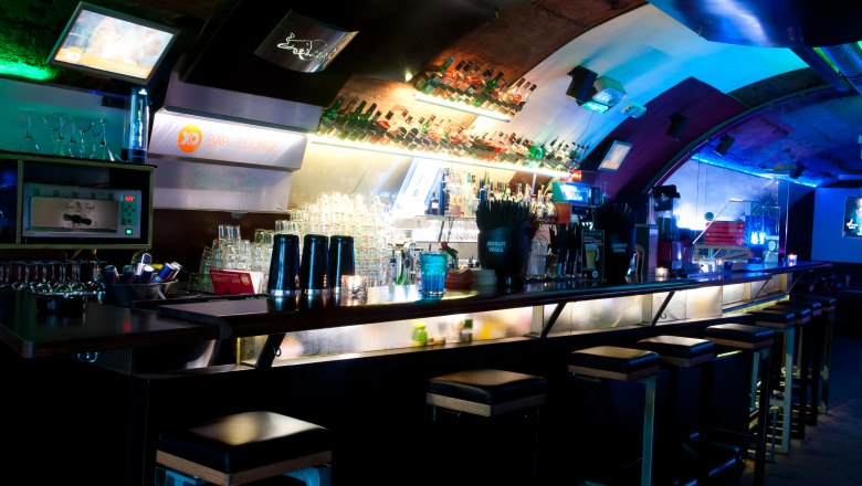 Interior view of a stylish bar with illuminated counter and bar stools.