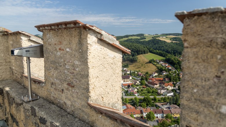 View of a town and green hills from a ruined castle.
