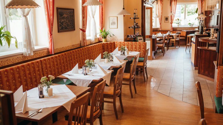 Cozy dining room with laid tables, wooden furniture and red curtains.