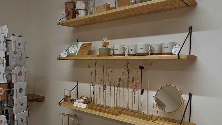 Shelves with handmade gifts such as wine bottles, cups, candles and dried flowers.
