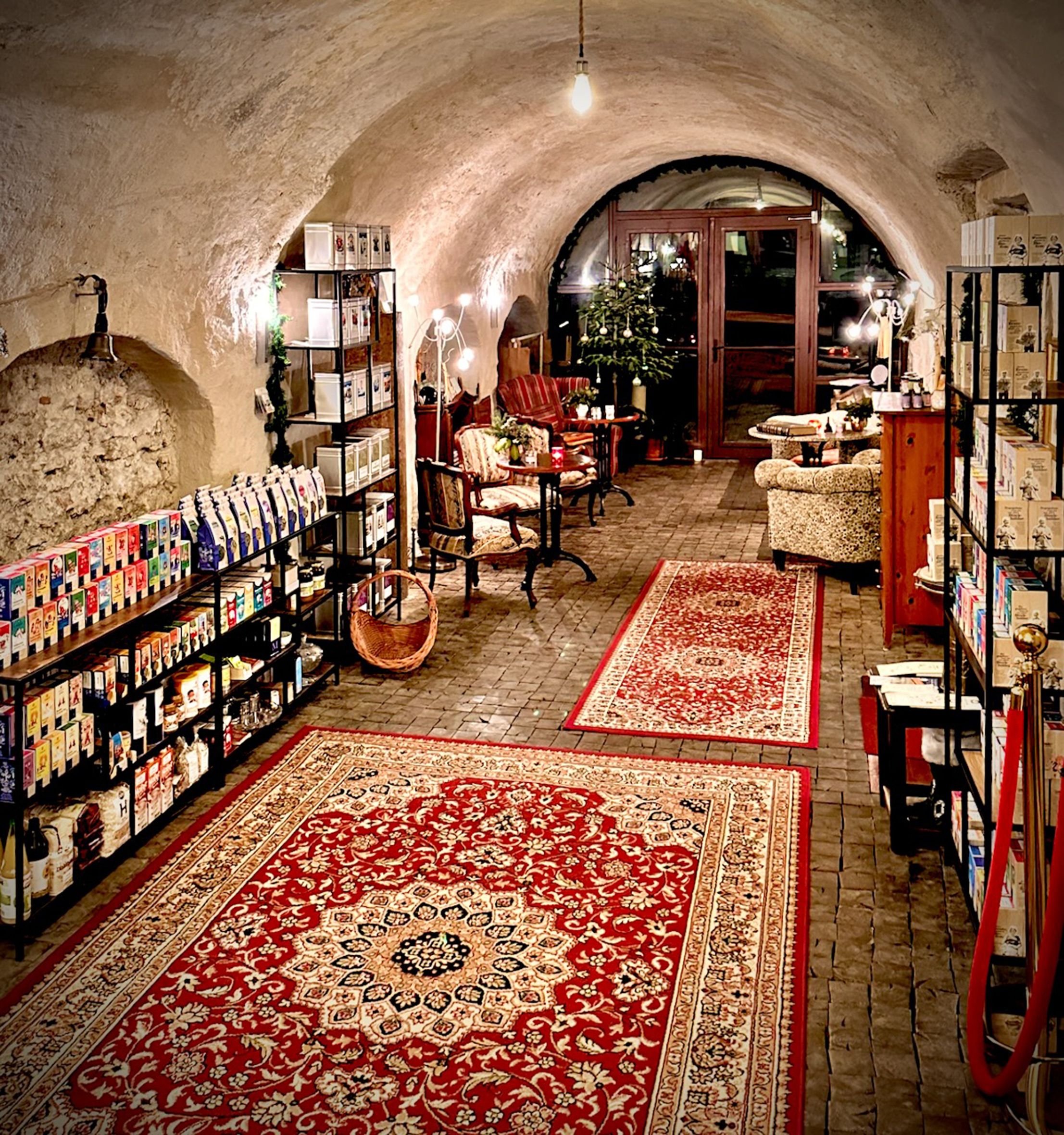 Cozy room with red carpets, shelves full of products and seating in the tea room.
