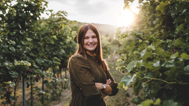 Woman standing between vines.