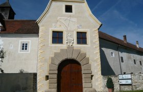 Entrance gate to Kreisbach Castle with sundial and coat of arms.
