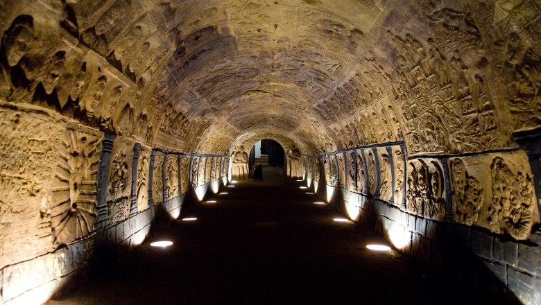 An illuminated tunnel decorated with reliefs in a historic cellar.