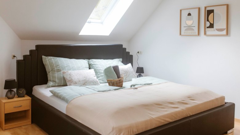 Cozy double room with skylight, modern bed and stylish decorations on the wall.