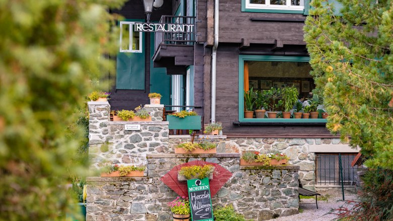 Exterior view of a restaurant with stone wall and plants.