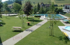 Green park with swimming pool and benches.