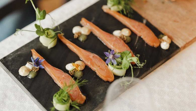Gourmet dish with salmon, herbs and flowers served on a slate plate.