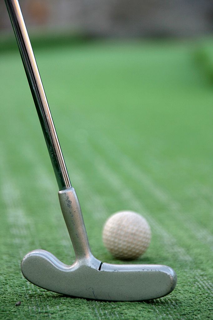 Minigolf clubs in front of green grass 