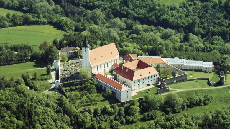 Aerial view of a monastery in the middle of a green landscape.