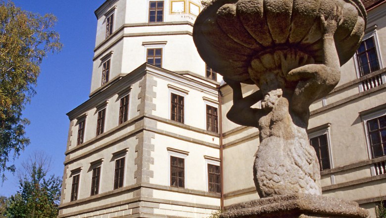 A historic building with a tower and a stone statue in the foreground.