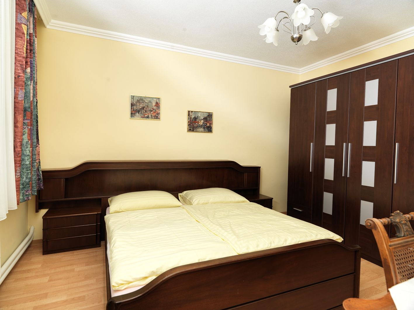 A cozy bedroom with a double bed, a large closet and two pictures on the wall.