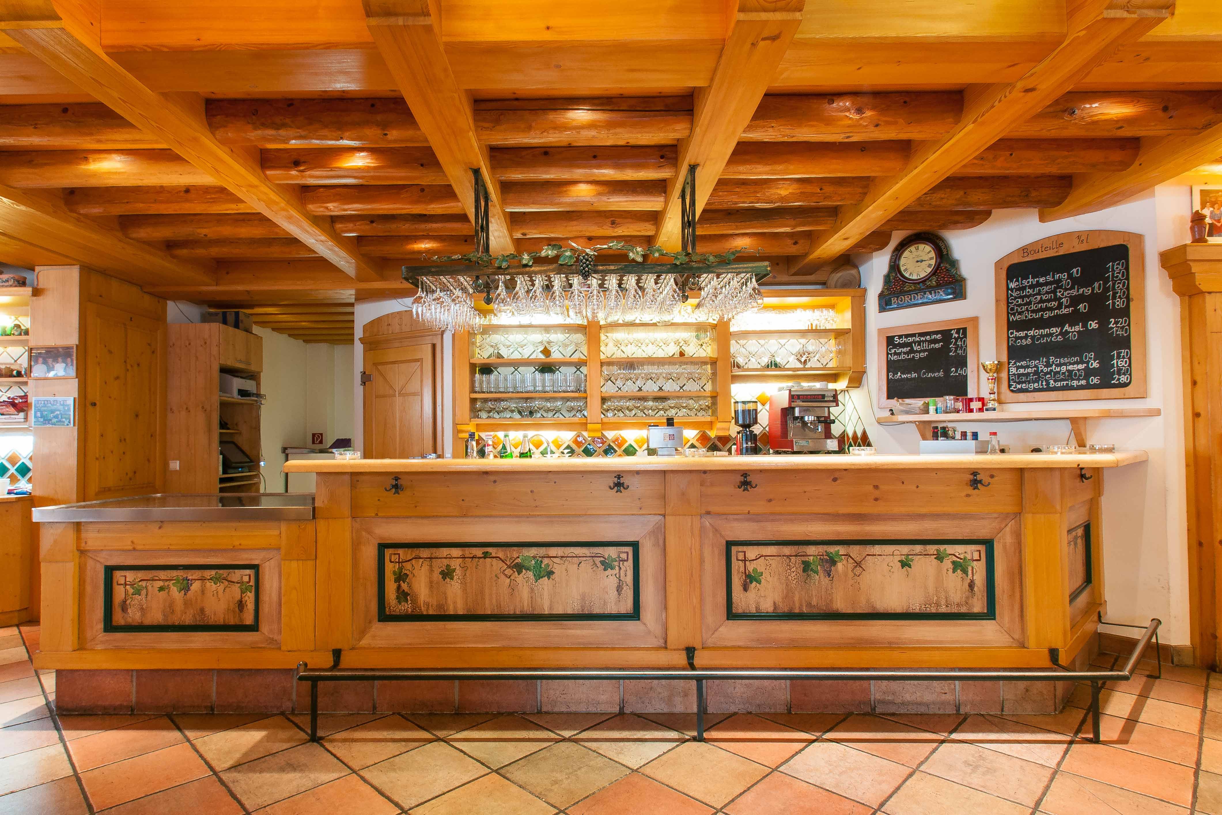 Rustic bar with wooden elements and wine glasses on the ceiling.