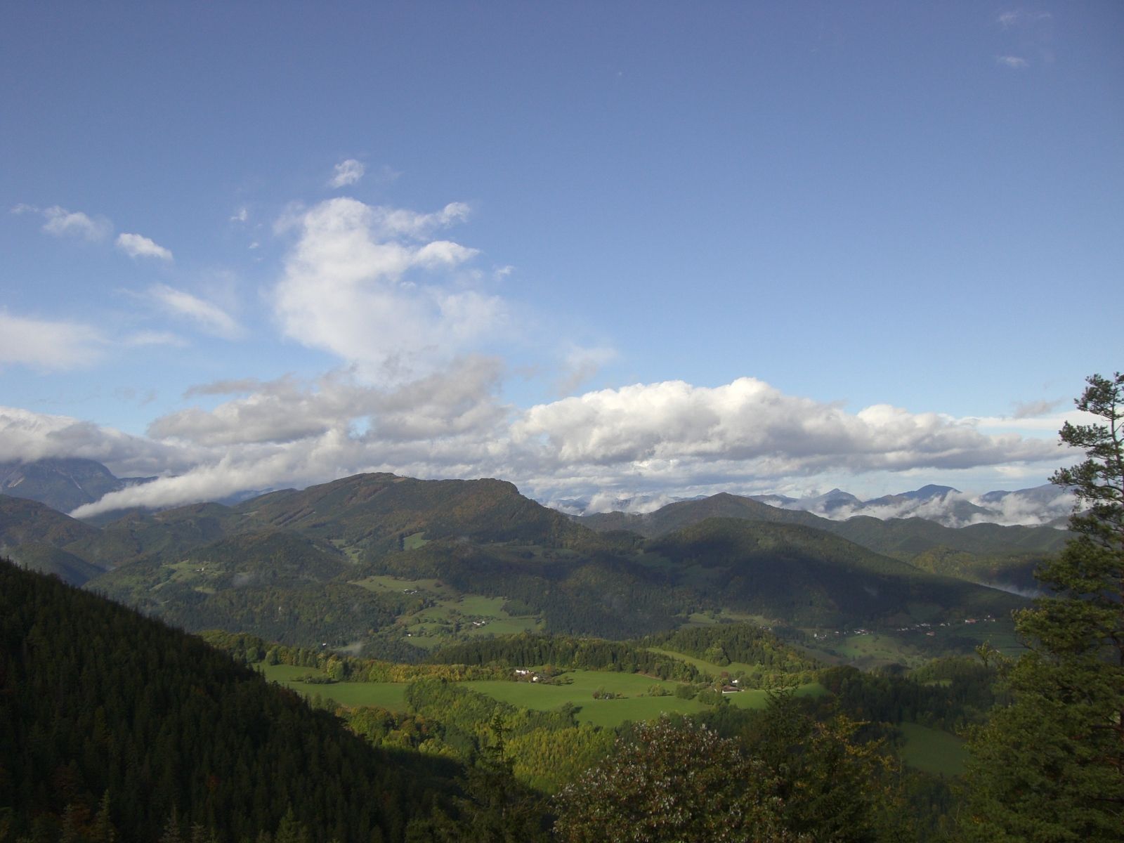 Panoramic view of a green mountain landscape under a blue sky with clouds.