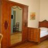 A traditionally furnished room with a wooden wardrobe, single bed and chair.