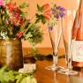 A bottle of Polz Frizzante with two glasses and a bouquet of flowers on a table.