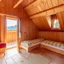 Bedroom with wood paneling, two beds, a window and an open door to the balcony.