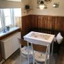 Small dining area with table, chairs and bench in a kitchen with wood paneling.