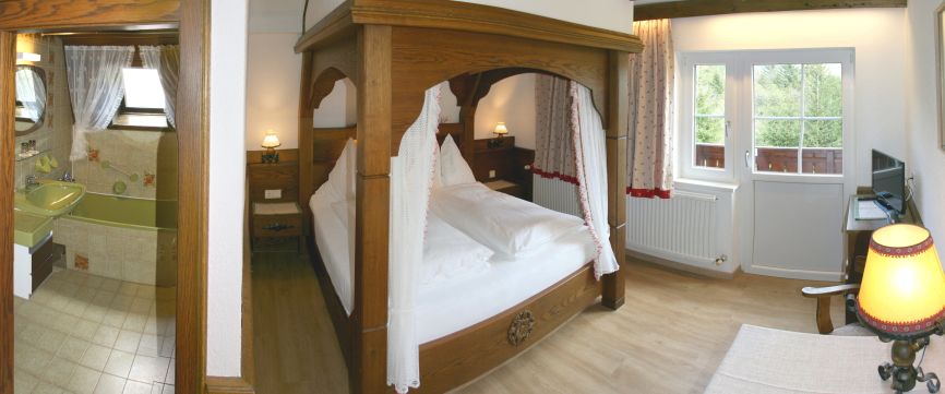 Cozy bedroom with four-poster bed, adjoining bathroom and balcony access.