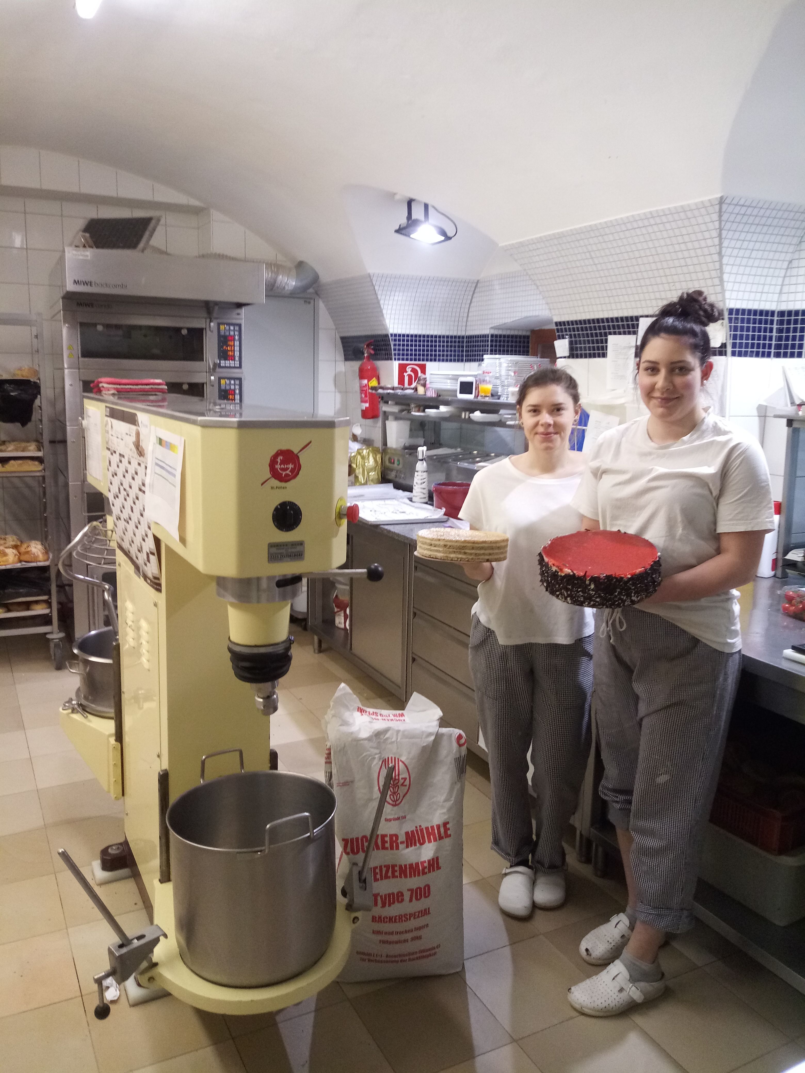 Two people in a bakery with a cake and a cake base.