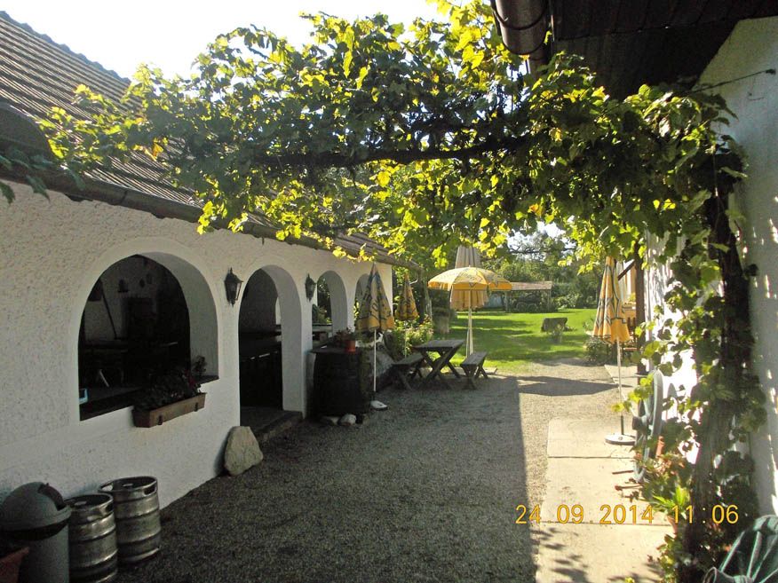 A cozy inn with white arches, a green pergola and yellow parasols in the garden.