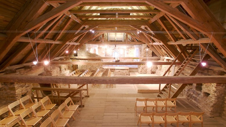 Interior view of the historic attic of the church with wooden beams and chairs.