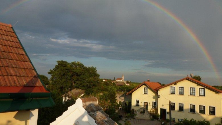 A rainbow over a village with yellow houses and red roofs.