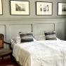 Bedroom with double bed, antique chair and framed pictures on the wall.