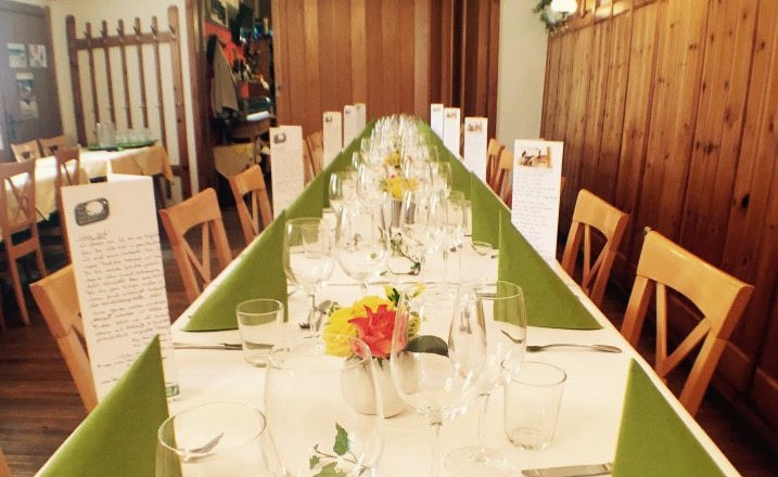 Long, festively laid table in a rustic dining room with wooden walls and decorations.