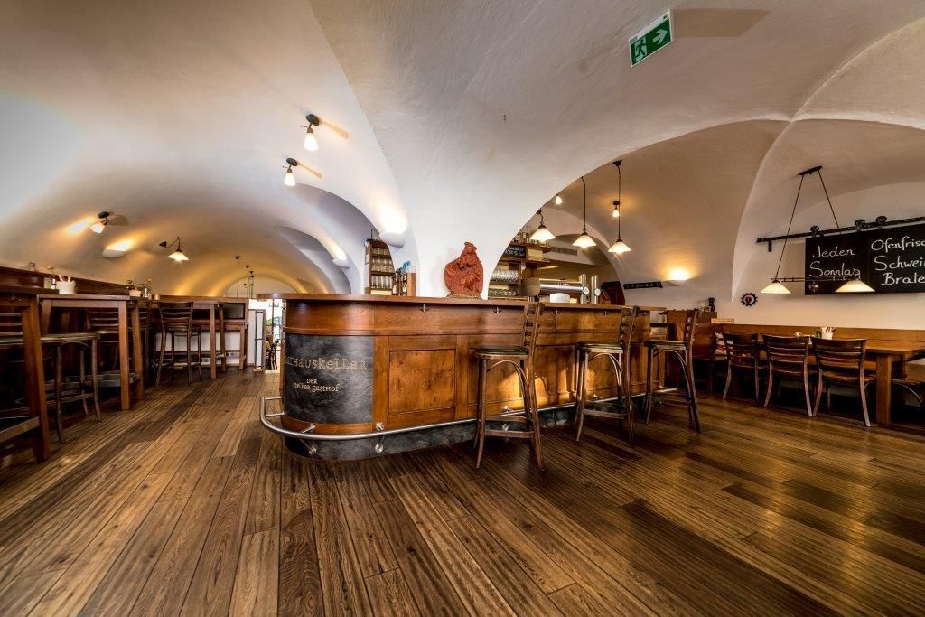 Interior view of a rustic dining room with wooden floor and vaulted ceiling.