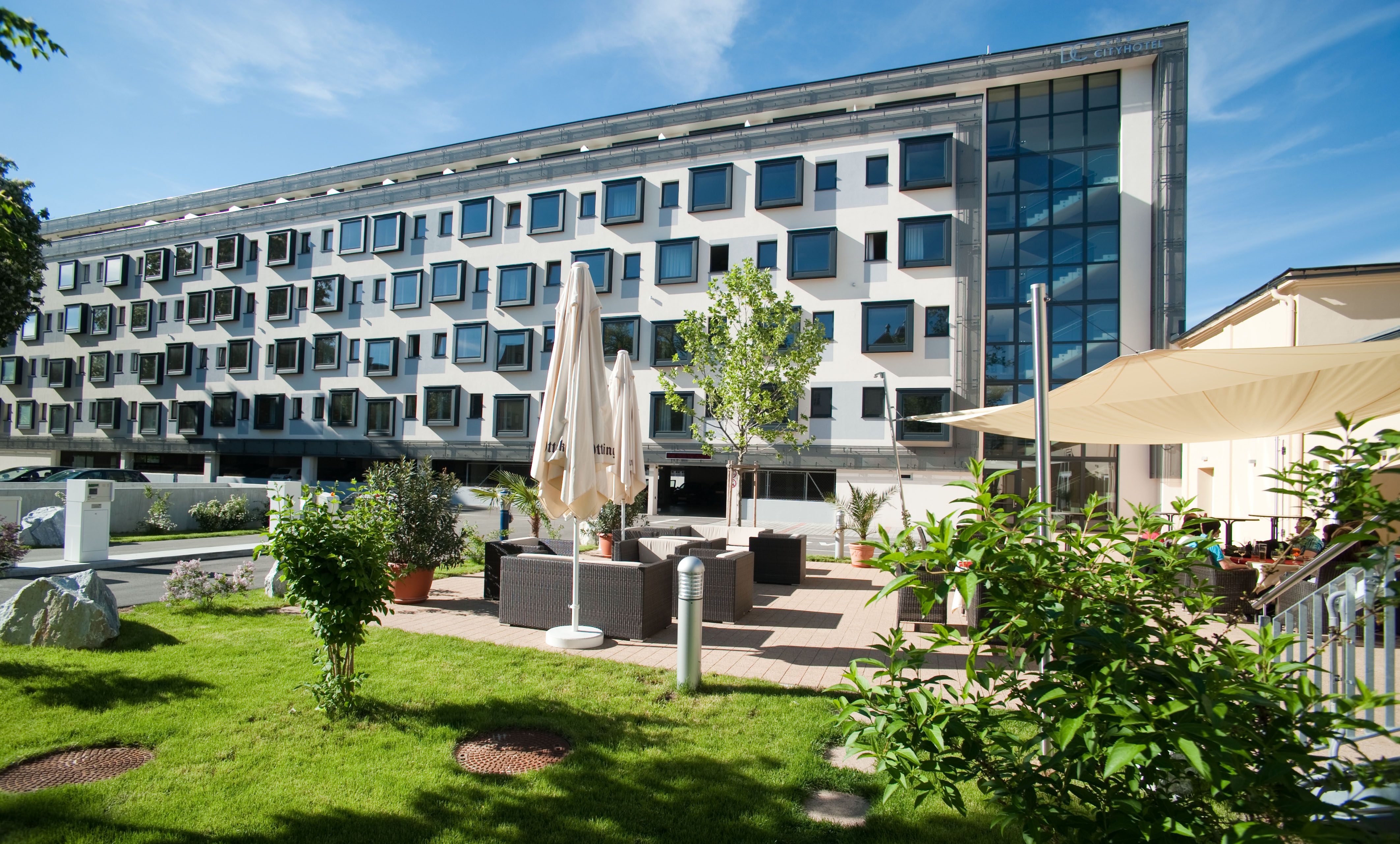 Modern building with many windows and garden area with seating.