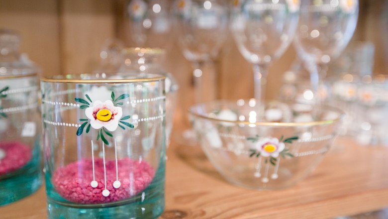 Glasses and bowls with floral motifs on a wooden shelf.