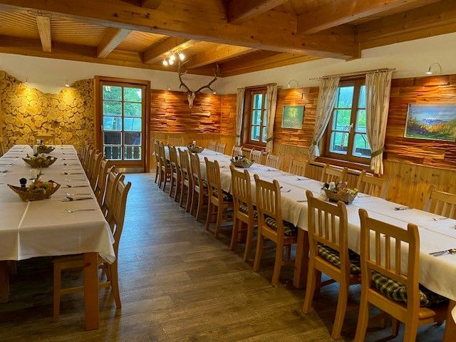 Rustic dining room with long, laid tables and wooden walls.