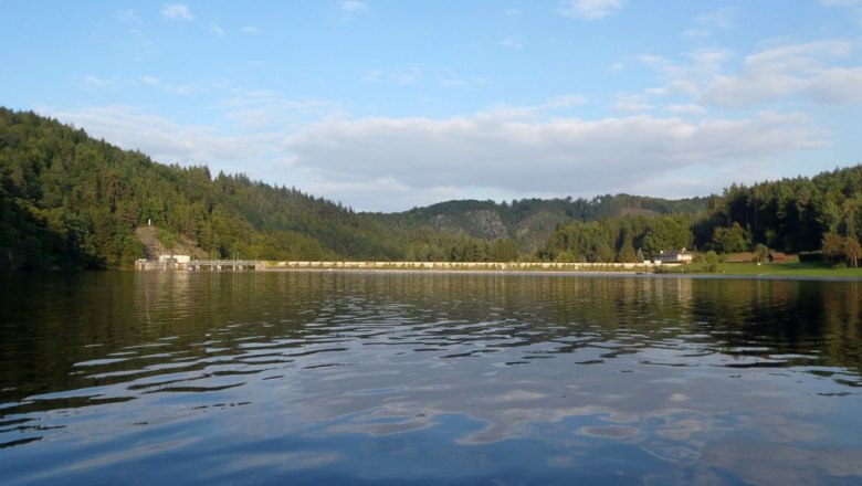 Thurnberg reservoir with wooded hills and dam in the background.