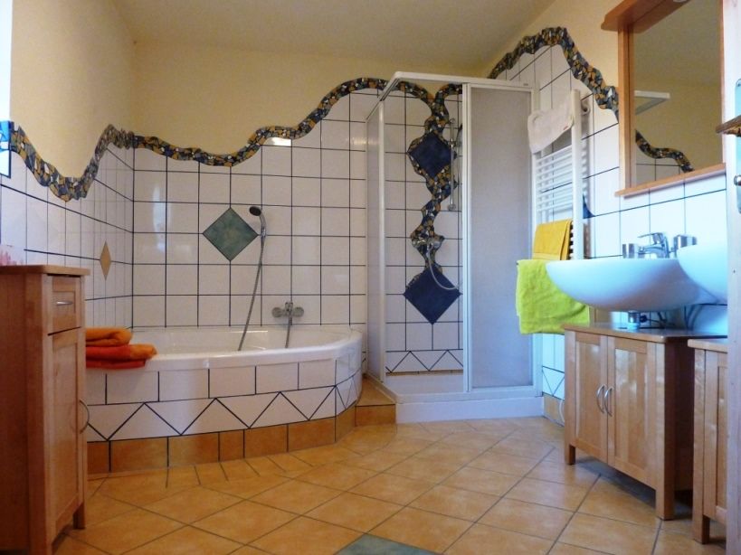 A bathroom with corner bath, shower, washbasin and tiles in blue and white.