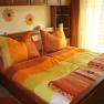 Cozy bedroom with sunflower decor and orange-yellow bed linen.