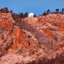 Rock face in the morning light with a full moon in the sky.