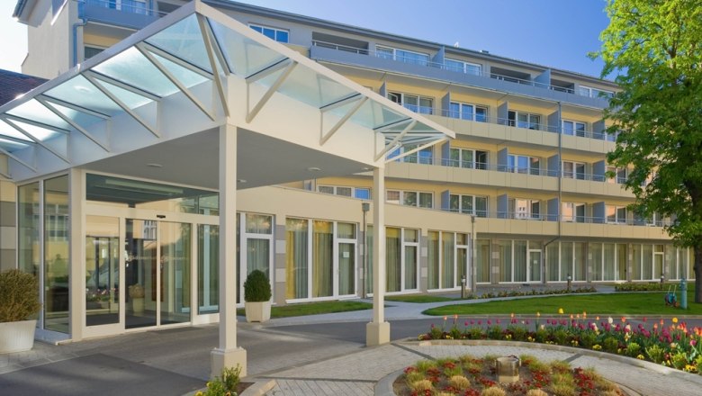 Modern building entrance with glass roof and garden.