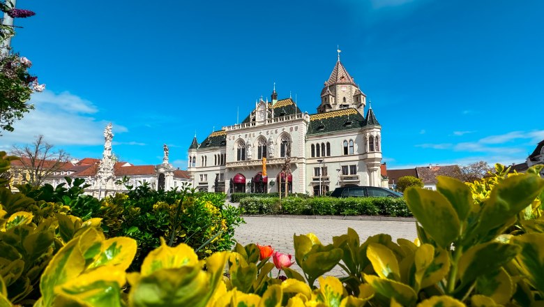 Korneuburg town hall with flowering plants in the foreground and a clear blue sky.