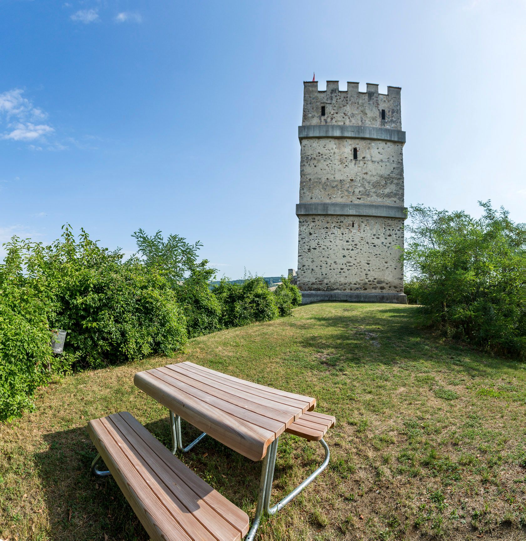 Fire tower of the Kirchschlag castle ruins with picnic table in the foreground.