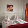 Bedroom with double bed, floral bedding, red picture and curtains.