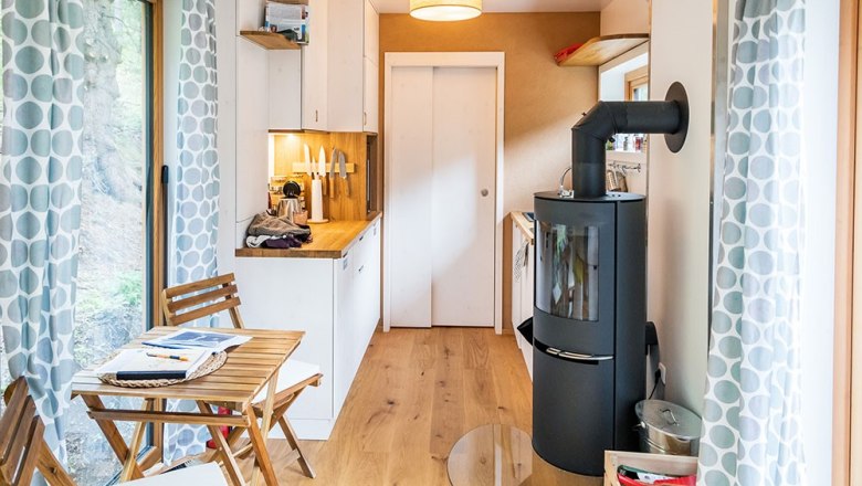 Interior view of a small kitchen with wood-burning stove and dining table.