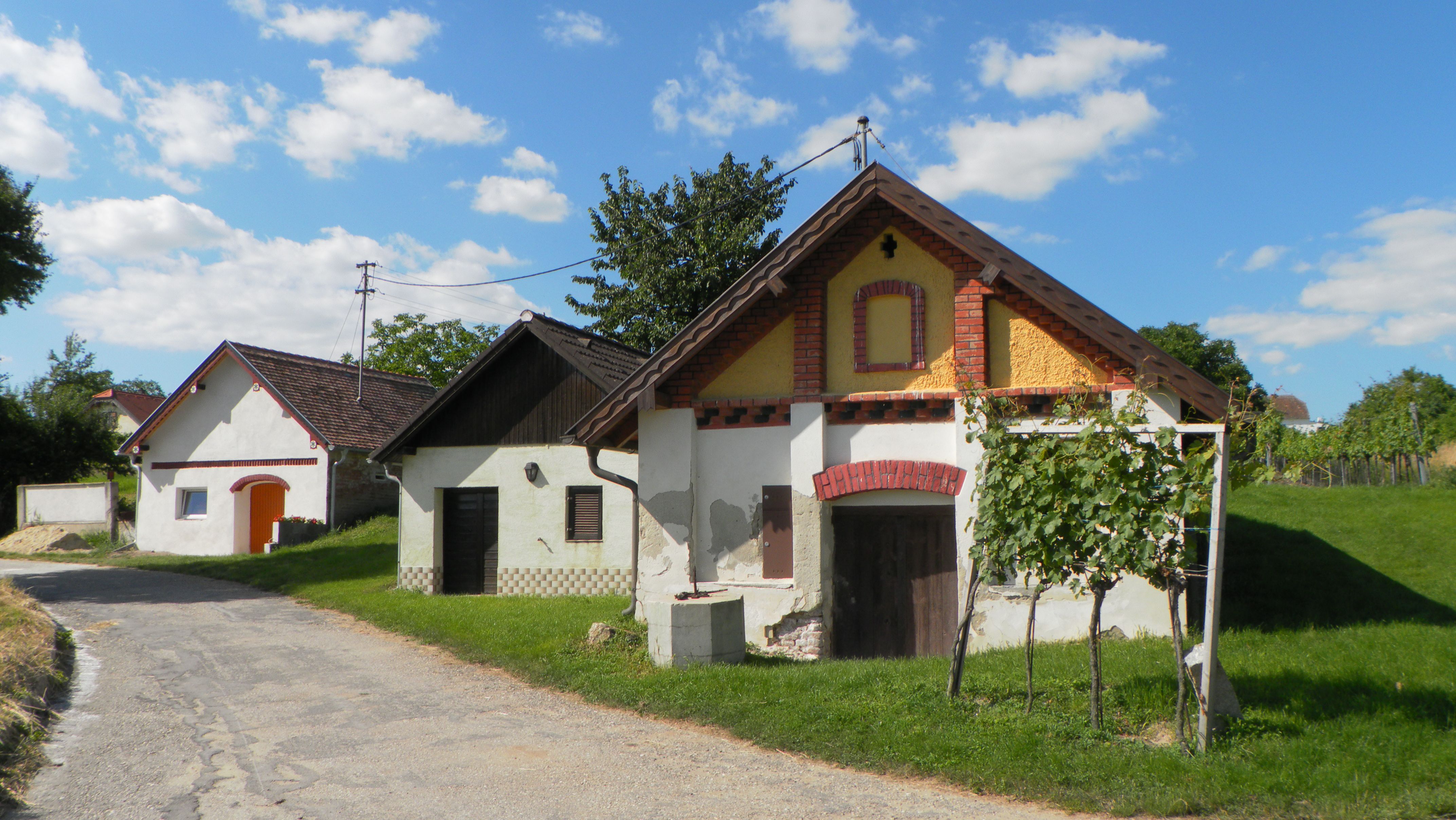 Traditional wine cellars in a rural setting with blue skies and clouds.