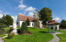 Fortified church of St. Stephen with statue and belfry in the foreground.