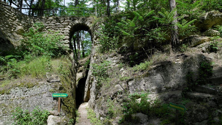 Stone bridge in Nexing Castle Park with green foliage and signpost.