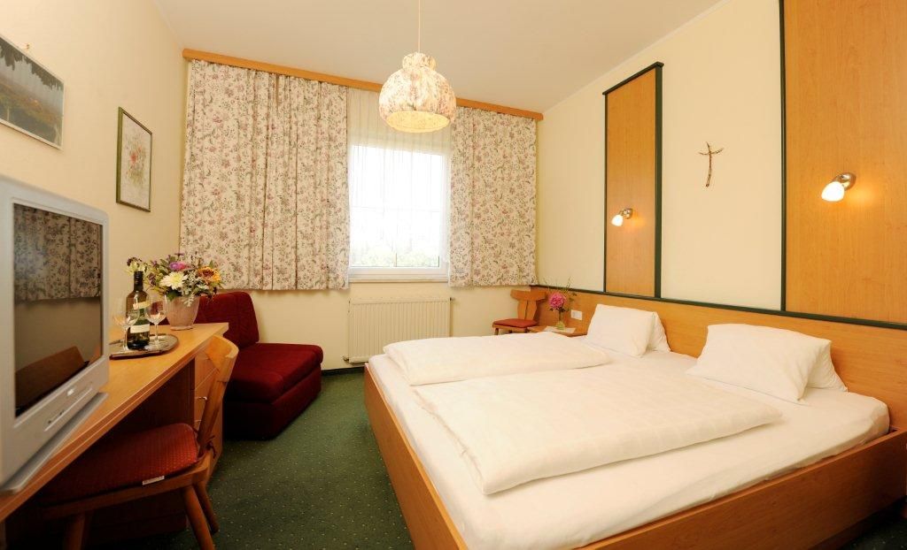 Comfortable hotel room with double bed, TV, flowers and curtains.