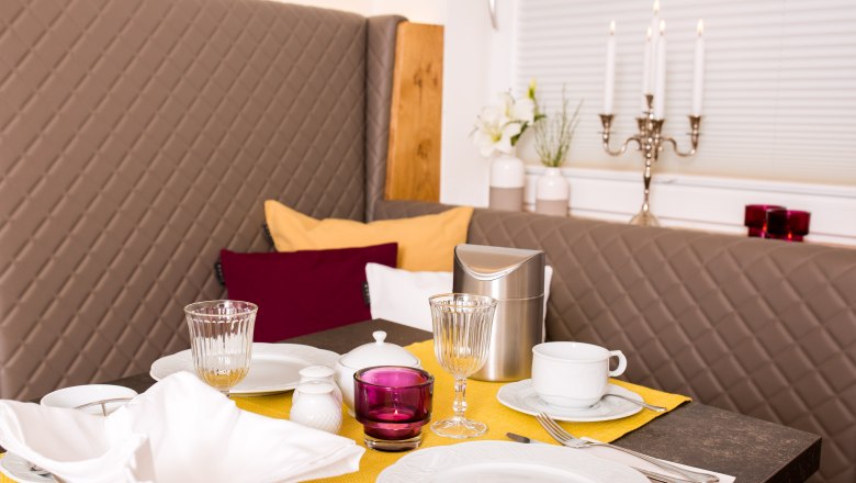 Elegant breakfast table with yellow runner, crockery, glasses and candlesticks.