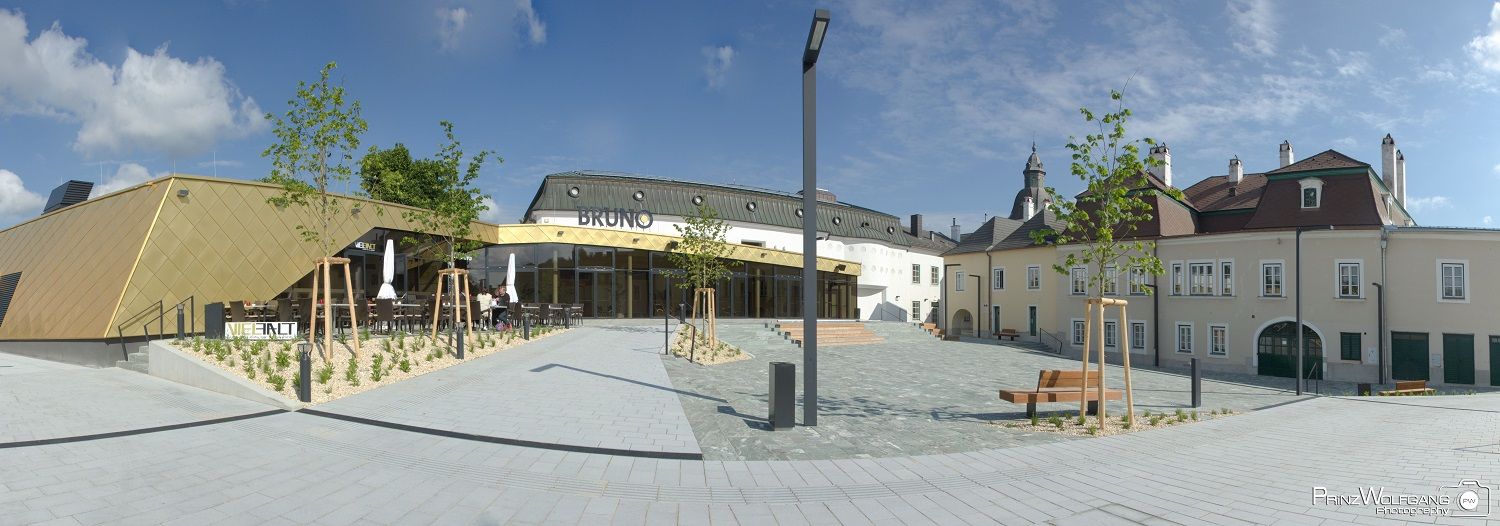 Modern architecture with golden facade and traditional building in the background, blue sky.